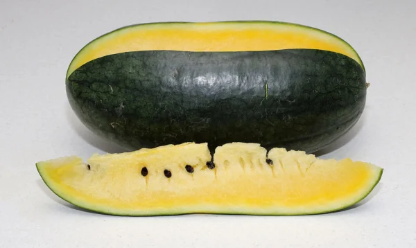 A yellow-fleshed watermelon with a cut wedge beside it