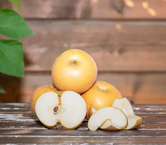 Whole and sliced yellow apples on a wooden table